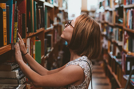 Woman in library looking for articles related to translator training